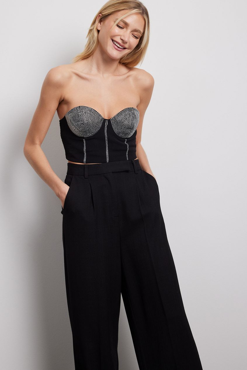 NA-KD corset bandeau top featuring a corset design, underwire cups with rhinestone embellishments, a smocked back and a side zipper closure. This top comes in black.